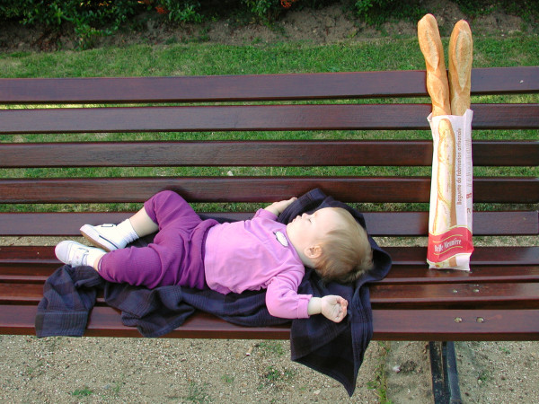 Child sleeping on a park bench